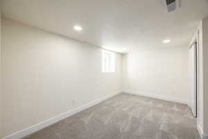 Basement with light colored carpet, recessed lighting, and a textured ceiling