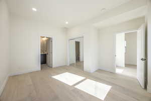 Primary bedroom featuring light wood finished floors, recessed lighting, a closet, and connected bathroom