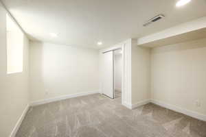Below grade area with light carpet, recessed lighting, and a textured ceiling