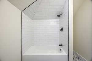 Full bath featuring bathtub / shower combination, lofted ceiling, and a textured ceiling