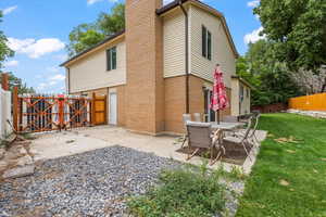Back of house featuring a fenced backyard, a patio area, a chimney, and brick siding
