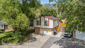 View of front of house with driveway, brick siding, a garage, and a mountain view