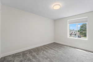 Carpeted spare room featuring baseboards