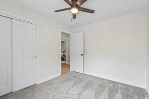 Unfurnished bedroom featuring carpet flooring, a ceiling fan, and a closet