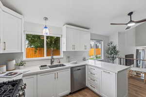 Kitchen with white cabinets, hanging light fixtures, and a peninsula