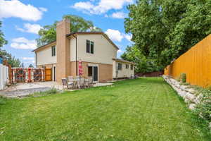 Back of property featuring a fenced backyard, a patio, a chimney, and brick siding