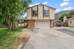 View of front facade featuring brick siding, a garage, driveway, and a mountain view