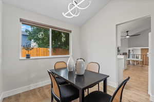 Dining space featuring vaulted ceiling, light wood-style floors, a ceiling fan, and a chandelier