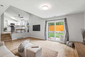 Living room featuring lofted ceiling, light wood finished floors, and ceiling fan