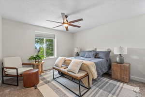 Bedroom featuring a ceiling fan, a textured ceiling, and carpet floors