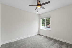 Carpeted spare room featuring baseboards and ceiling fan