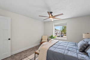Bedroom with carpet, a ceiling fan, and a textured ceiling