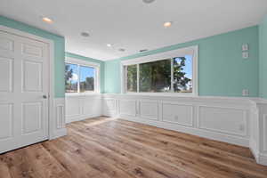 Unfurnished dining area featuring light wood finished floors, wainscoting, a decorative wall, and recessed lighting