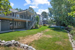 View of green lawn with a patio, a trampoline, stairway, and a wooden deck