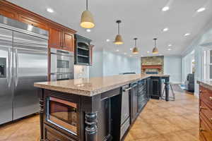 Kitchen featuring built in appliances, open floor plan, hanging light fixtures, crown molding, and recessed lighting