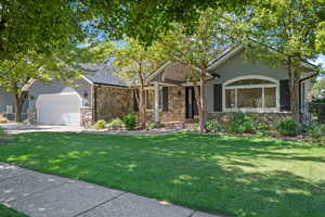 View of front of home featuring stone siding, a garage, a front yard, and concrete driveway