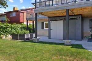 Rear view of property featuring a balcony, a lawn, and a patio