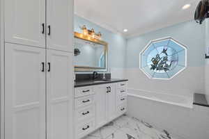 Bathroom with vanity, a bath, light marble finish floors, and ornamental molding