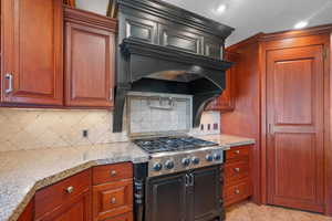 Kitchen with backsplash, stainless steel gas cooktop, light tile patterned floors, light stone counters, and recessed lighting