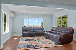 Living area with ornamental molding, wood finished floors, an AC wall unit, and recessed lighting
