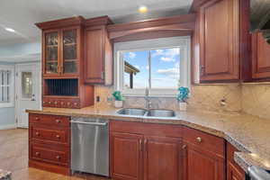Kitchen with dishwasher, light stone counters, light tile patterned floors, glass insert cabinets, and crown molding