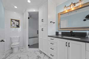 Bathroom featuring ornamental molding, vanity, a shower stall, tile walls, and light marble finish floors