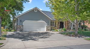 View of front of home featuring driveway, stone siding, and an attached garage