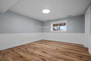 Spare room with a wainscoted wall and light wood-style floors