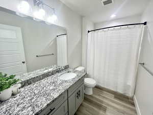 Bathroom with dark wood-style flooring, vanity, curtained shower, and recessed lighting