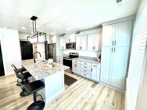 Kitchen with a kitchen breakfast bar, stainless steel appliances, light stone counters, hanging light fixtures, and recessed lighting