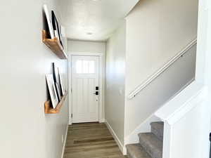 Doorway to outside featuring stairway, a textured ceiling, and wood finished floors