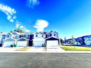 Traditional-style house with stone siding, a residential view, driveway, and an attached garage
