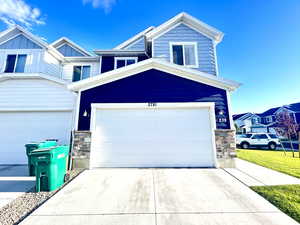 View of front of home featuring stone siding, concrete driveway, and board and batten siding