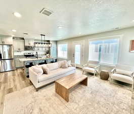 Living room featuring light wood-style flooring, recessed lighting, and a textured ceiling