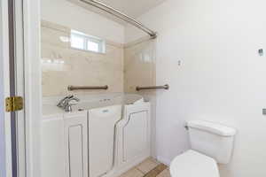 Full bathroom with light tile patterned flooring and washtub / shower combination
