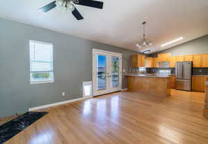 Kitchen with light wood-style floors, freestanding refrigerator, a peninsula, lofted ceiling, and decorative light fixtures