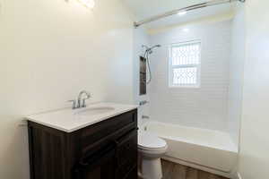 Full bathroom with shower / tub combination, vanity, and dark wood-type flooring