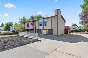 Split foyer home with driveway, a chimney, and brick siding