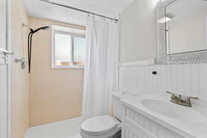 Bathroom with a shower stall, vanity, and a wainscoted wall
