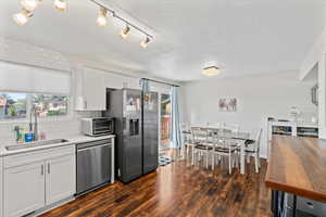 Kitchen featuring white cabinets, decorative backsplash, appliances with stainless steel finishes, dark wood finished floors, and light stone counters