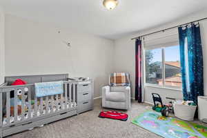 Carpeted bedroom featuring a crib and baseboards