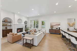 Living area with recessed lighting, light wood-style floors, a lit fireplace, and built in features