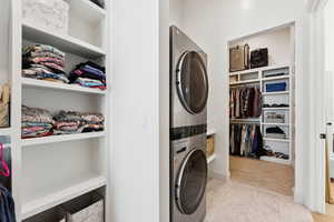 Laundry area featuring built in shelves and stacked washer and clothes dryer