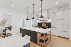 Kitchen with light wood-style flooring, recessed lighting, dark stone countertops, hanging light fixtures, and a kitchen bar