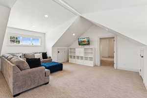 Living room with vaulted ceiling, light colored carpet, and recessed lighting
