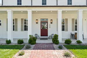 Property entrance with covered porch and a yard