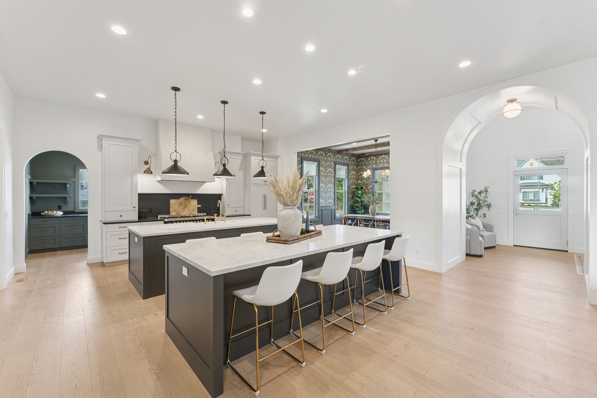 Kitchen featuring arched walkways, a breakfast bar, white cabinets, healthy amount of natural light, and recessed lighting