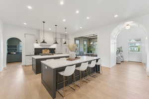 Kitchen featuring arched walkways, a breakfast bar, white cabinets, healthy amount of natural light, and recessed lighting