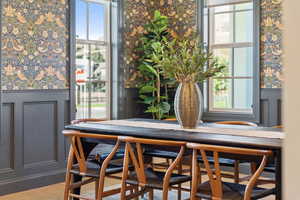 Dining space with wainscoting, a decorative wall, wallpapered walls, and wood finished floors