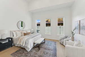Bedroom with light wood finished floors and a towering ceiling